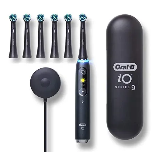 Oral-B iO Series 9 electric toothbrush with interactive color display, magnetic charger, and six brush heads on bathroom counter