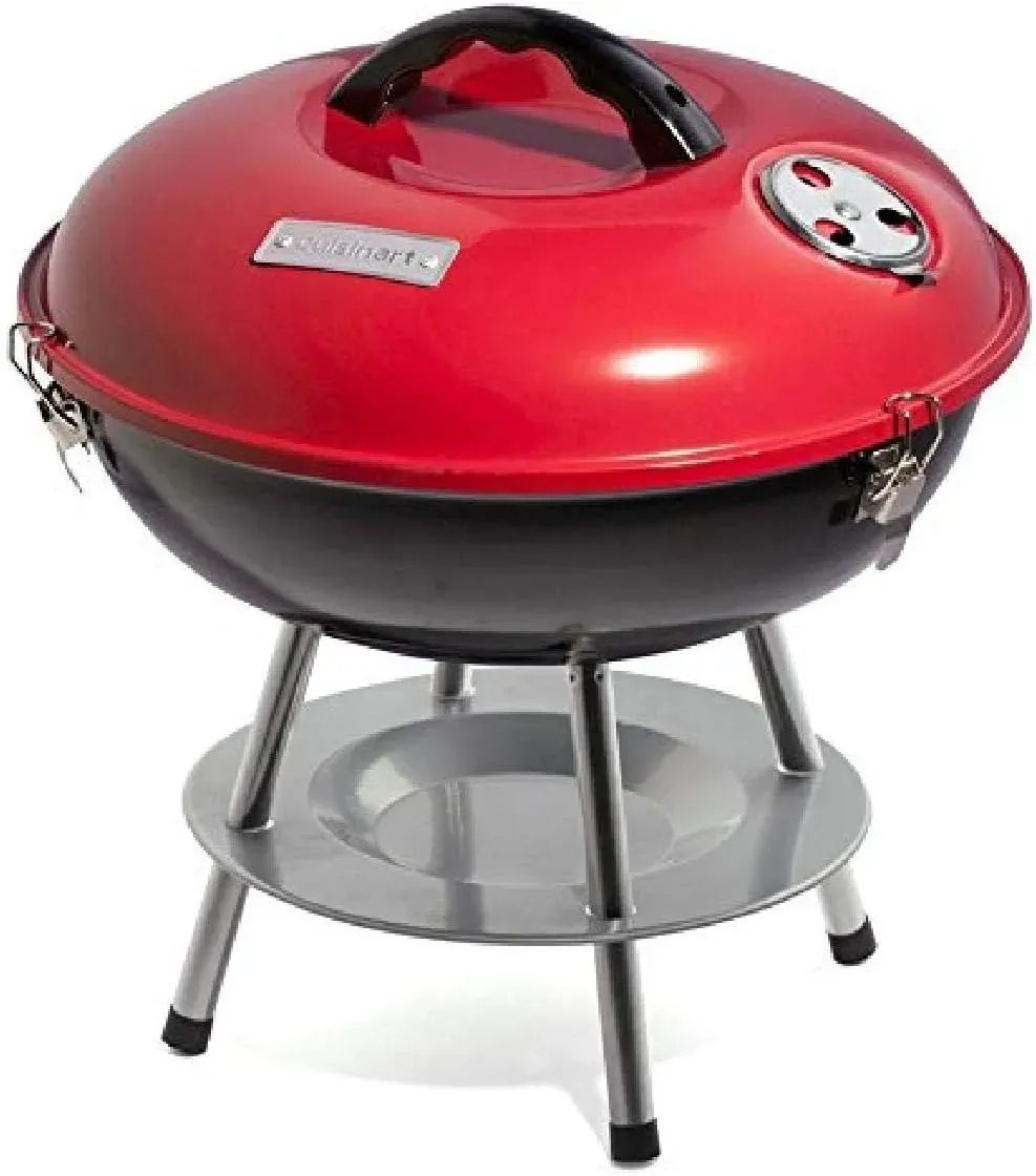 Cuisinart CCG190RB 14 inch portable charcoal grill cooking on a picnic table at a campsite